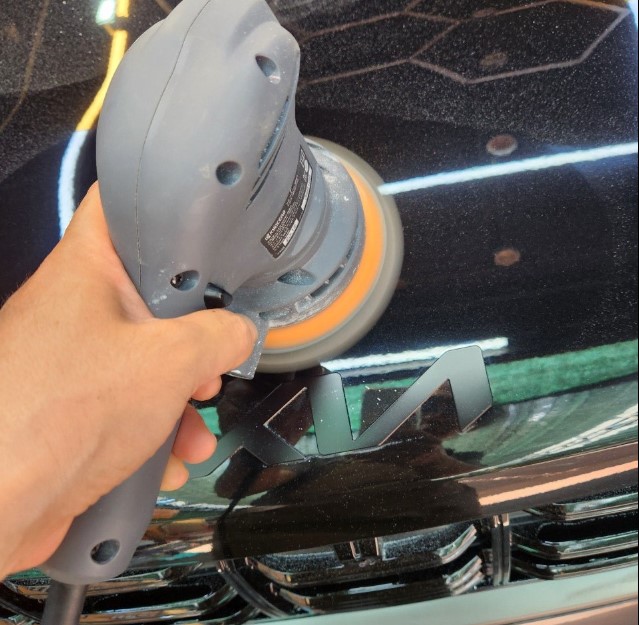 Machine polisher removing fine scratches from an automotive paint surface