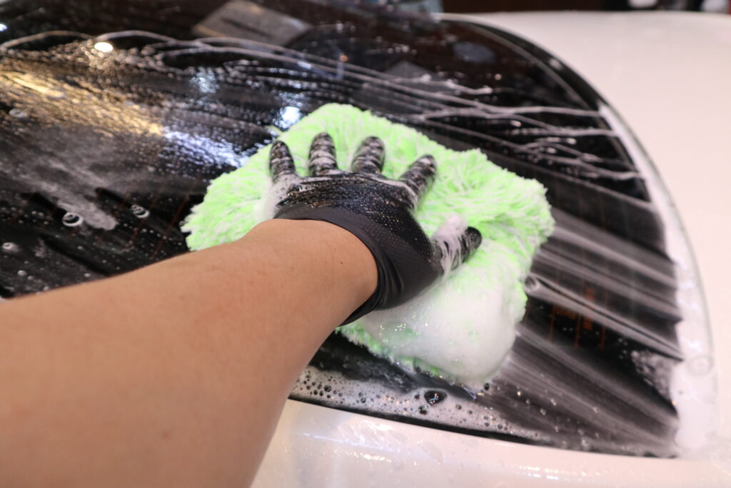 Microfiber wash mitt used on a foamed car panel during contact washing