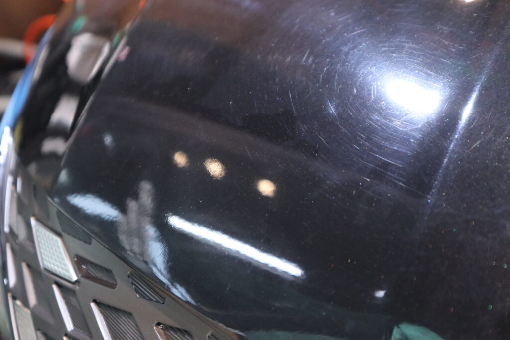 Wash-induced marring and swirl marks visible on car paint under inspection lighting