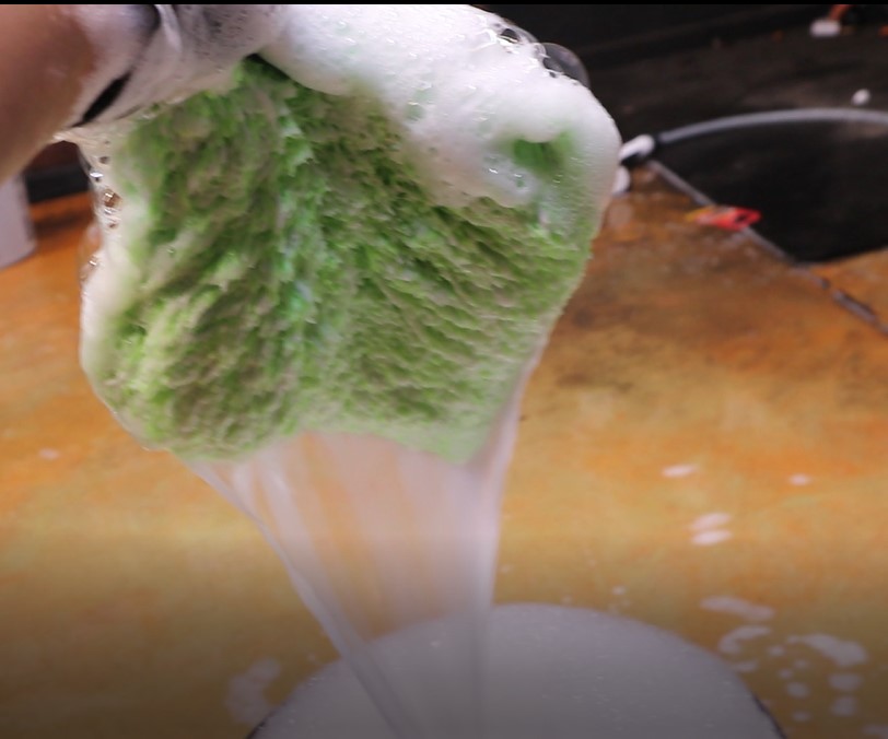 Long-pile microfiber wash mitt fully saturated with shampoo solution and releasing water