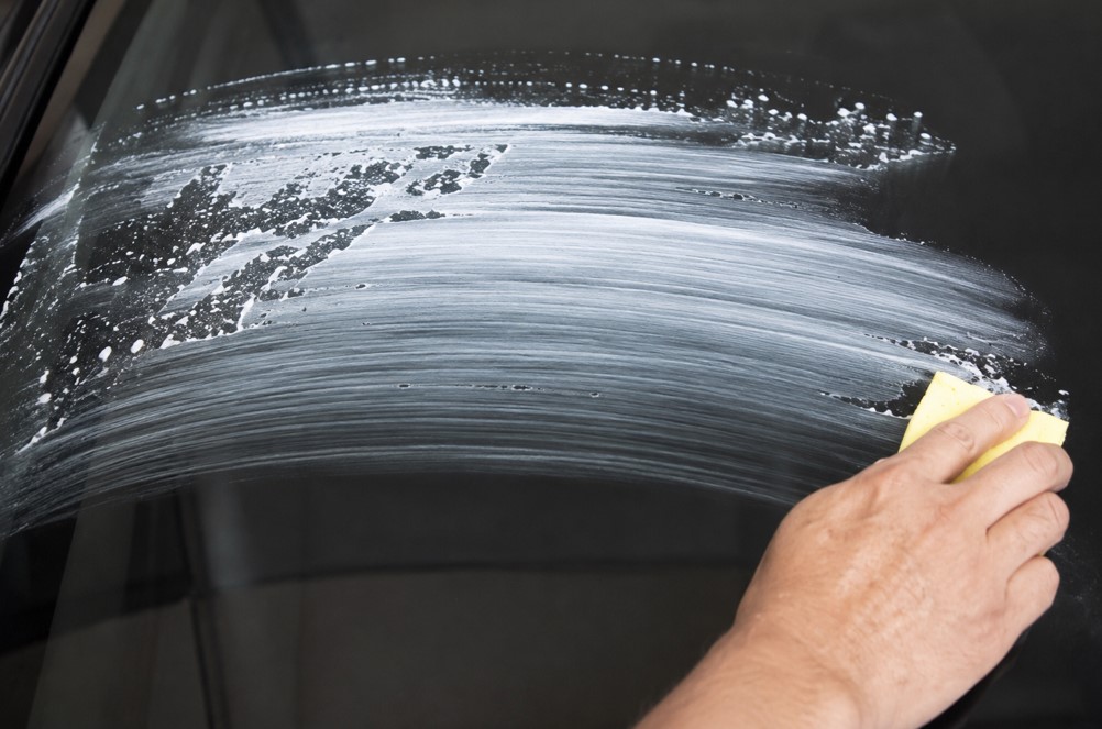 Water beading on a car windshield during oil film removal