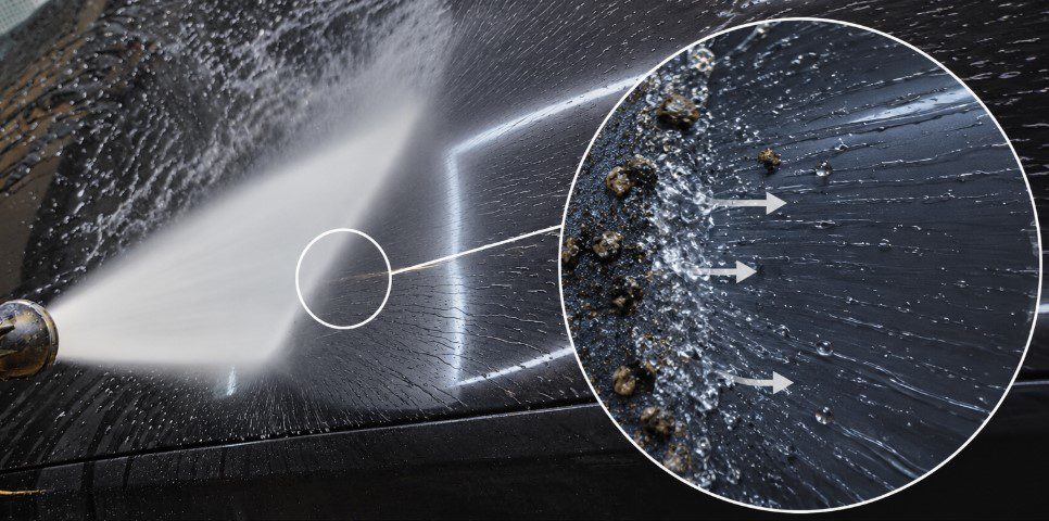 High-pressure water separating loosened contamination from car paint and carrying it away