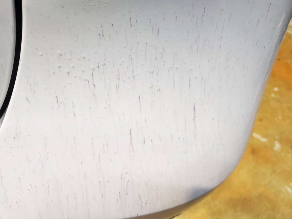 Purple iron remover reaction on ferrous contamination on white car paint