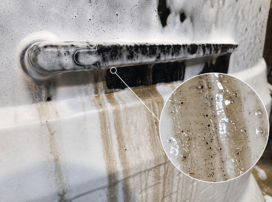 Close-up of road film being wetted by pre-wash cleaner as the contamination layer becomes saturated and loosened